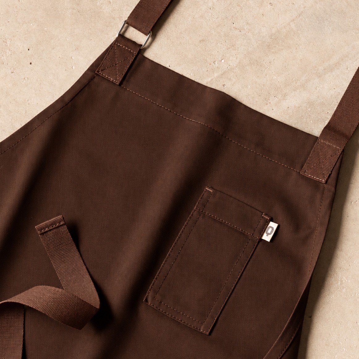 Professional brown apron with a chest pocket, an alternative to black in hospitality uniforms Professional brown apron with a chest pocket, an alternative to black in hospitality uniforms